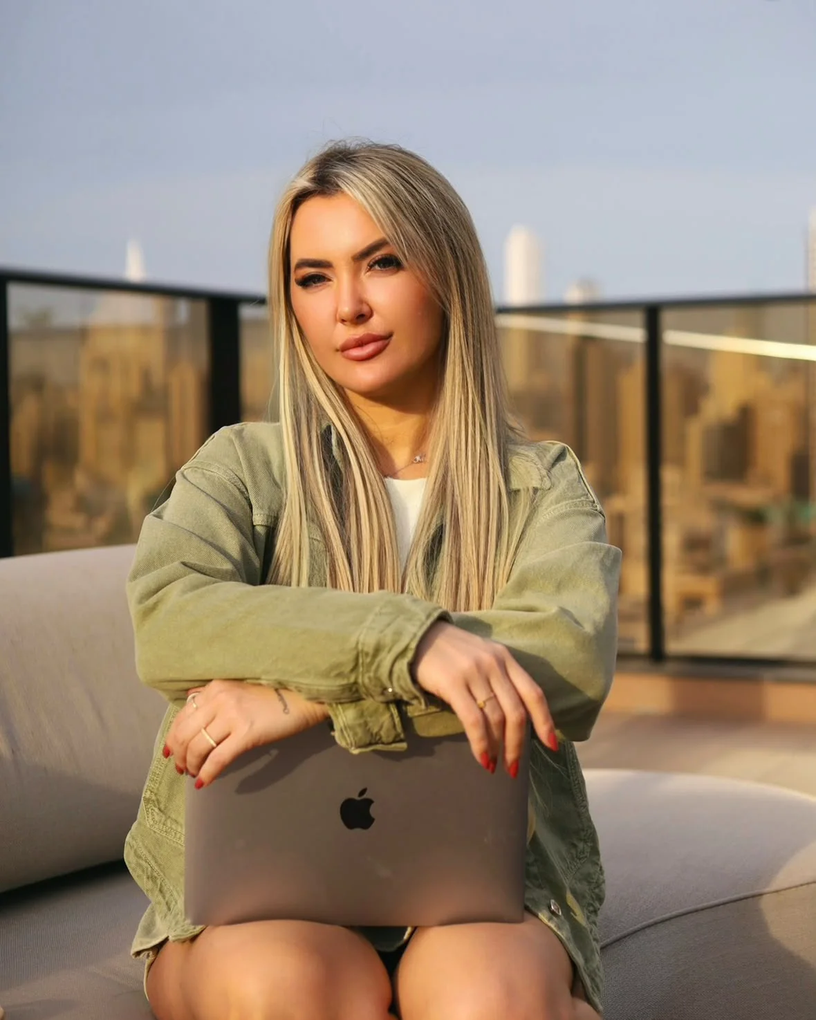 Graziele Dalpra sentada na varanda com o notebook no colo